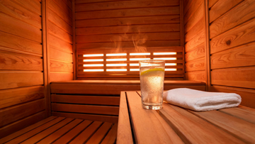 A warm cedar infrared sauna interior viewed from inside, low bench angle, soft amber glow from near-infrared heater panels…