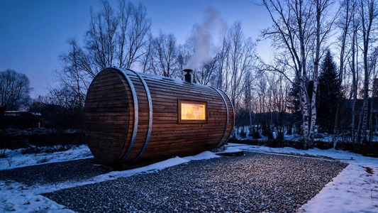 A compact cedar barrel sauna sitting on a gravel pad in a Canadian backyard, warm amber glow from a small window set into…