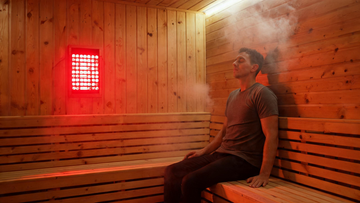 9) — Warm cedar sauna interior with a wall-mounted red light panel glowing, one person seated calmly; steam-lit, Cedar…