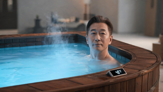 A calm person submerged to the shoulders in a sleek modern cold plunge, faint vapour over a steady waterline and a glowing digital temperature readout