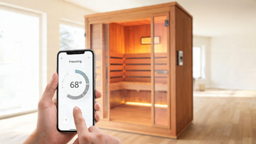 [IMAGE SLOT 1 - HERO 16:9 - phone app showing a home infrared sauna preheating, cedar cabin in a bright Canadian home. Also…