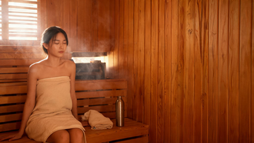 9) — Calm, steam-softened cedar sauna interior with warm low light; a person sitting relaxed, towel and water bottle nearby.…