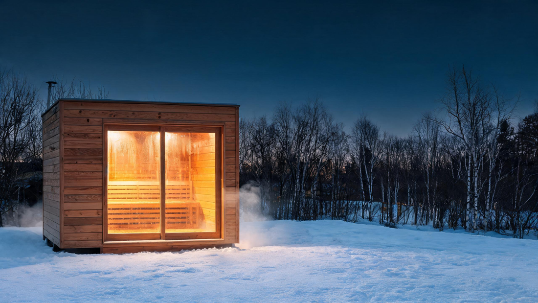 Hero, 16:9. A modern eco-friendly cedar sauna set in a snowy Canadian backyard at golden hour: warm amber interior glow…