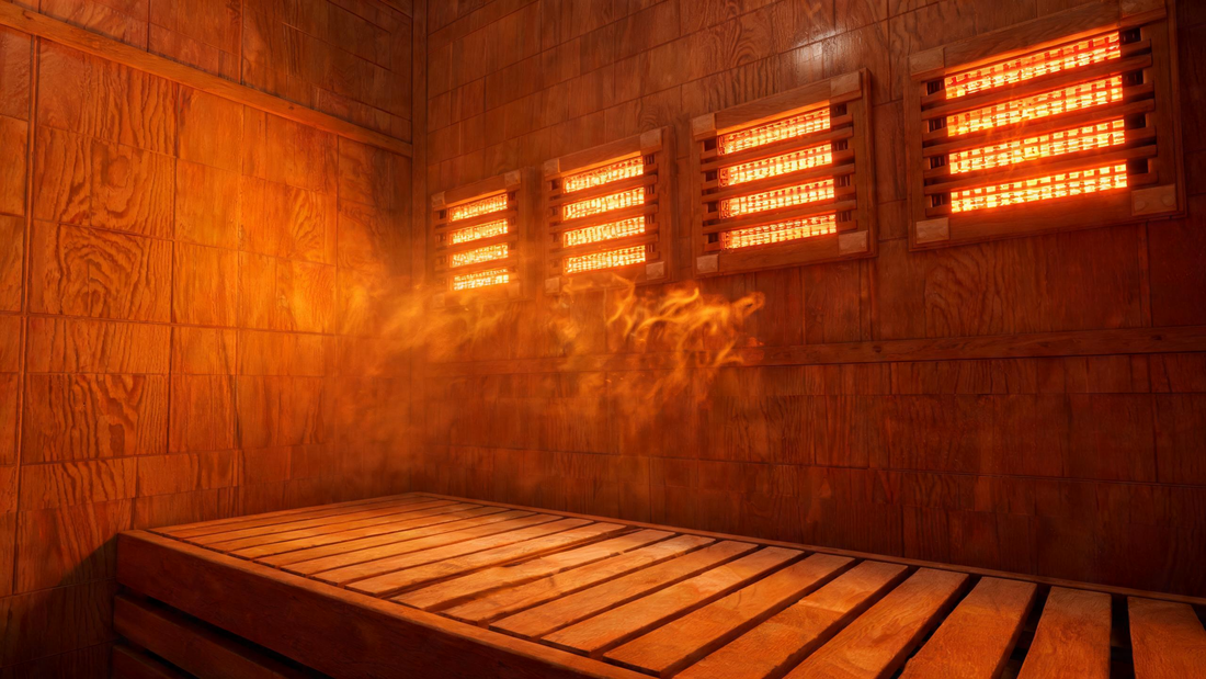 Interior of a premium full-spectrum infrared sauna, warm cedar walls glowing amber under active near-infrared heater panels, visible radiant heat shimmer