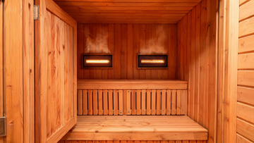 A premium indoor infrared sauna cabin built from rich Grade-A Canadian cedar, door open to reveal the warm amber interior, vertical cedar bench slats and