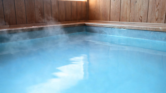 Crystal-clear Glacier-blue cold plunge water like polished glass with faint cold mist and a warm cedar surround